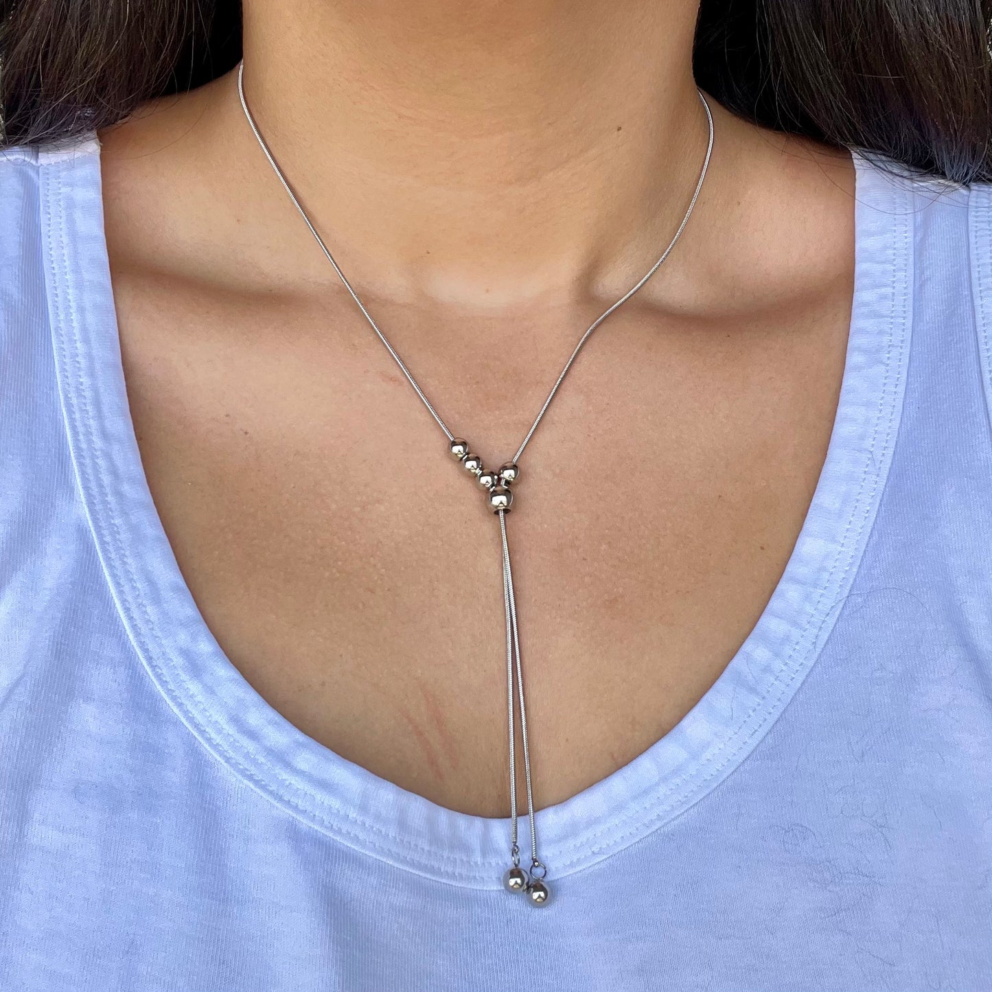 Silver necklace with beads worn by a person on a light blue shirt