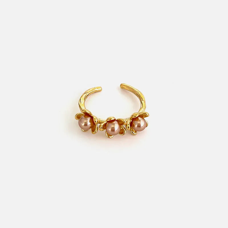 Gold ear cuff with pearls on a light beige background