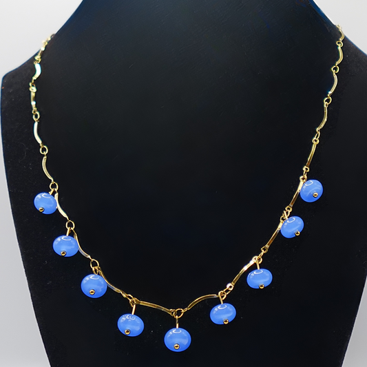 Necklace with blue beads and gold chain on a black mannequin against a white background