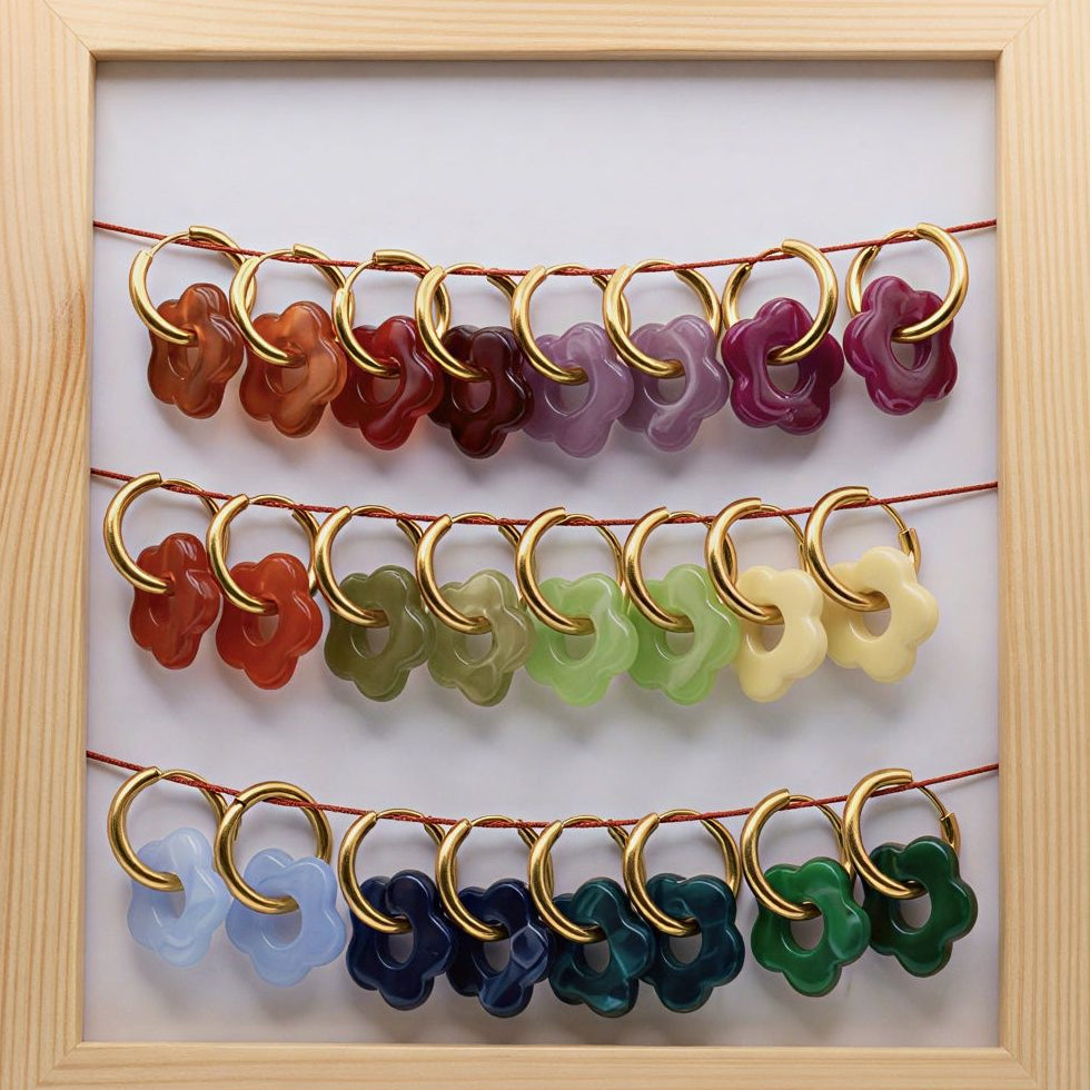 Set of colorful earrings in a wooden frame on a white background