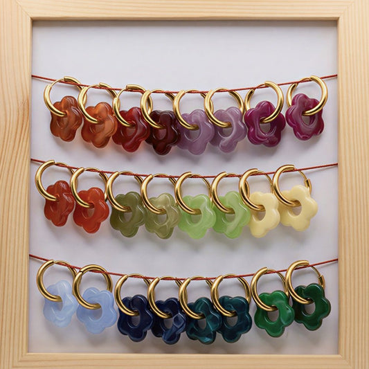 Set of colorful earrings in a wooden frame on a white background