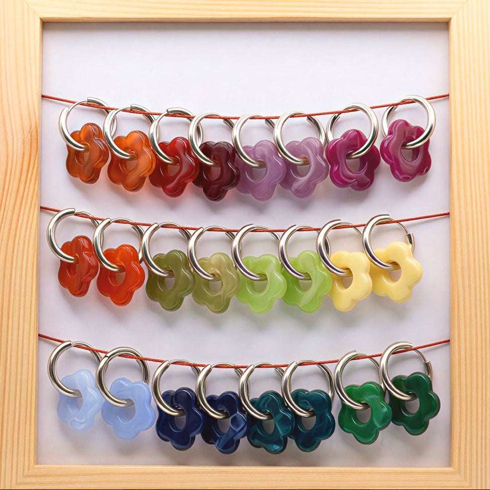 Colorful flower-shaped hooks displayed in a wooden frame on a white background
