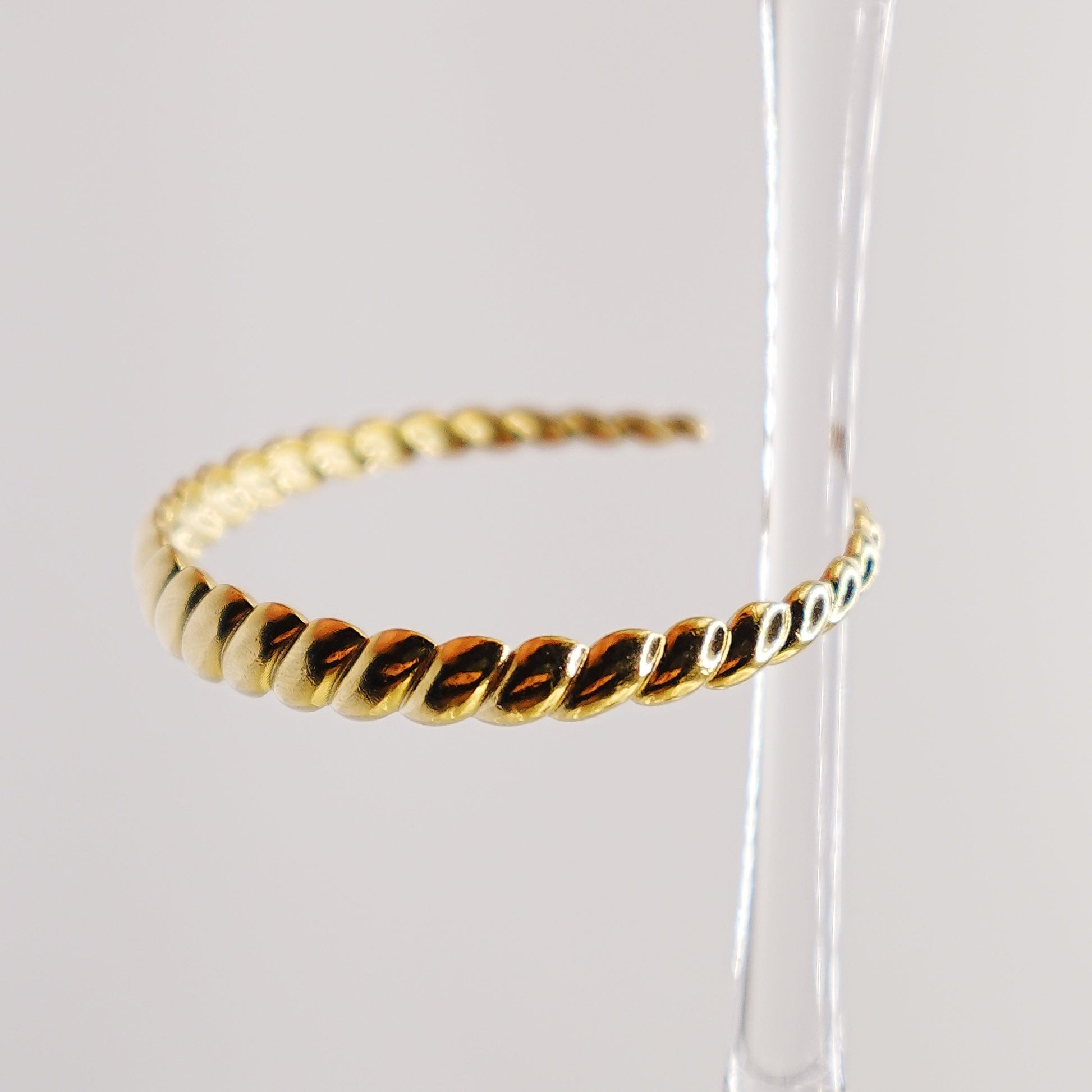 Gold hoop earrings on a clear stand against a white background