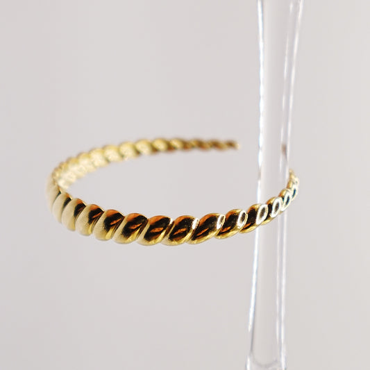 Gold hoop earrings on a clear stand against a white background