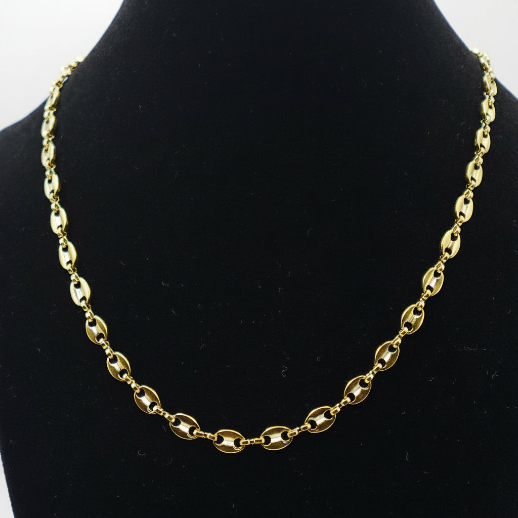 Gold chain necklace on a black mannequin bust against a white background