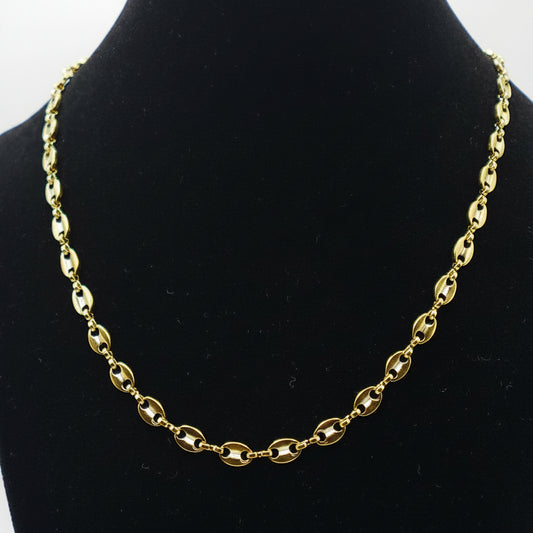 Gold chain necklace on a black mannequin bust against a white background