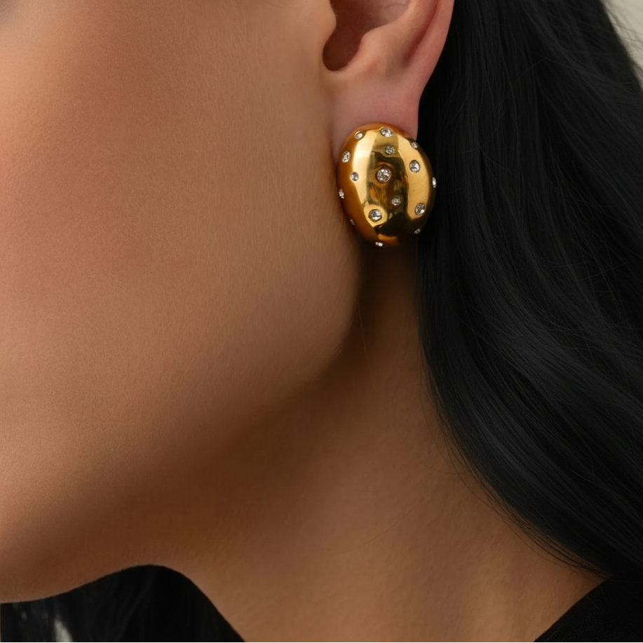 Gold earring worn by a person with dark hair.