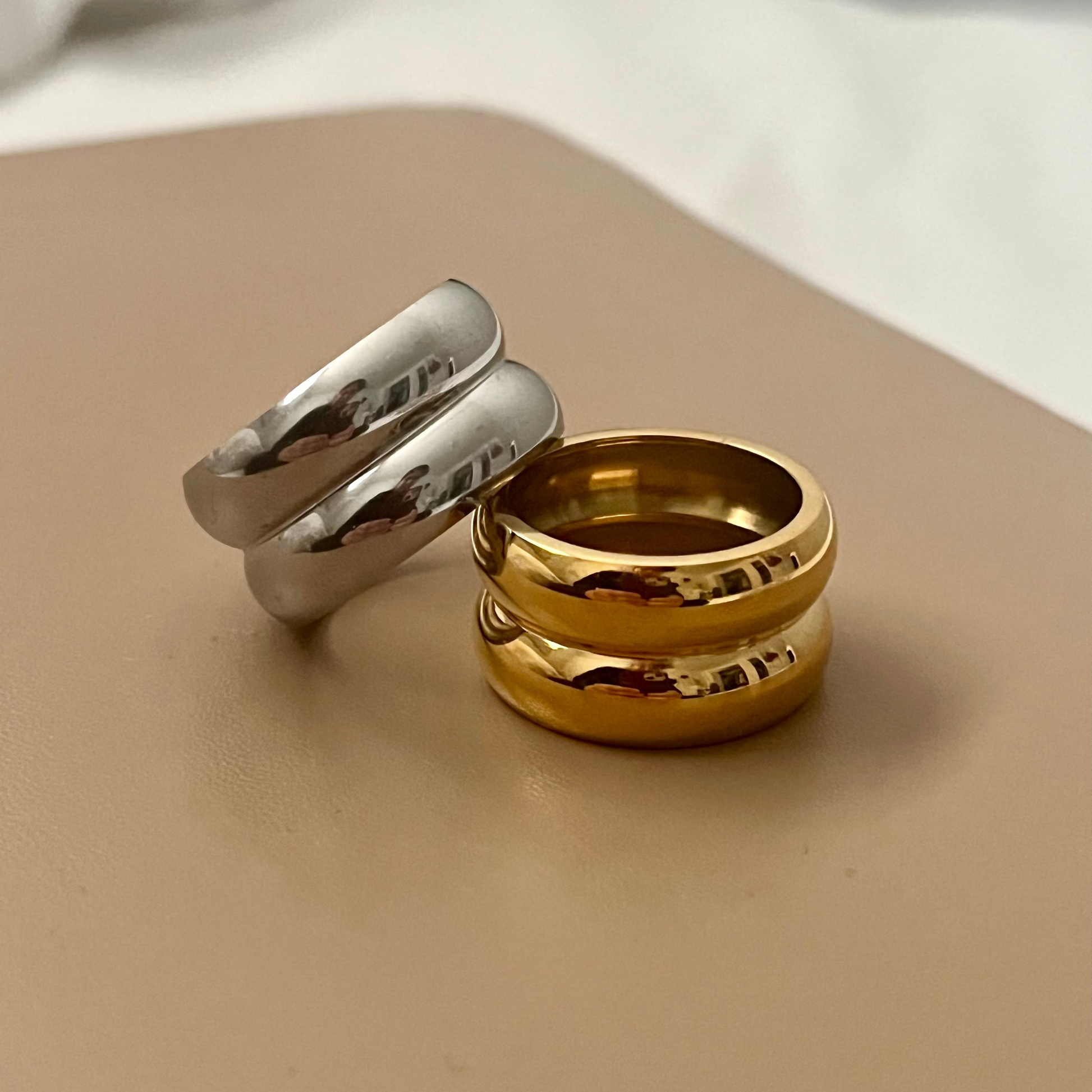 Gold and silver rings on a beige surface