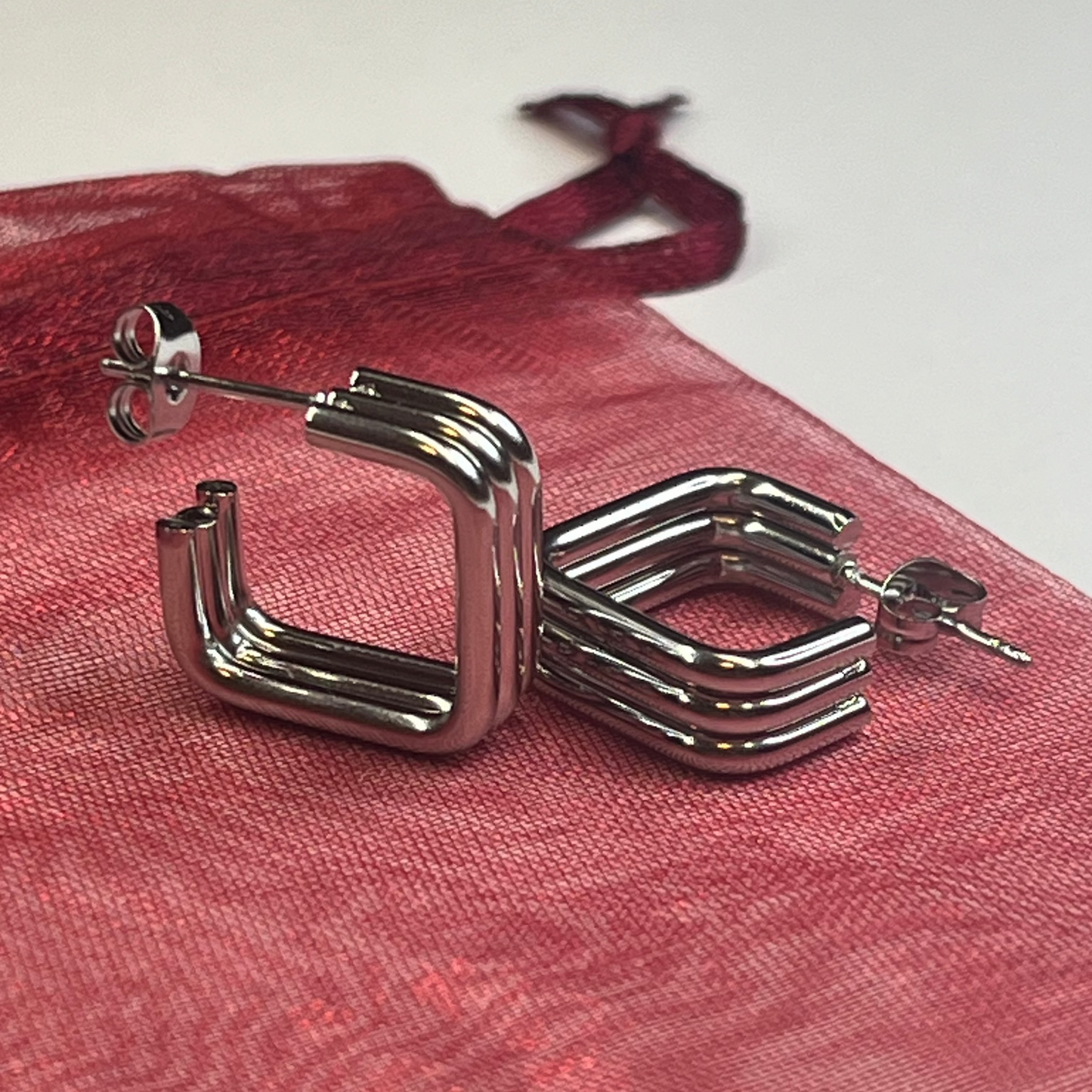 Silver hoop earrings on a red fabric background