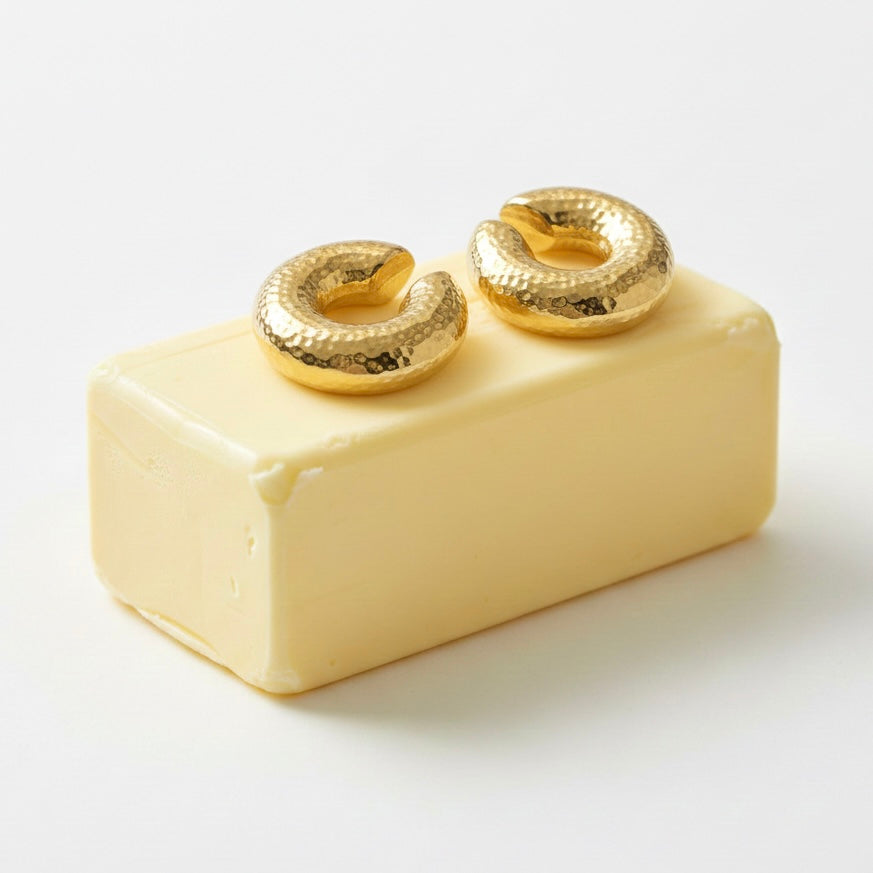 Gold earrings on a block of white soap against a white background