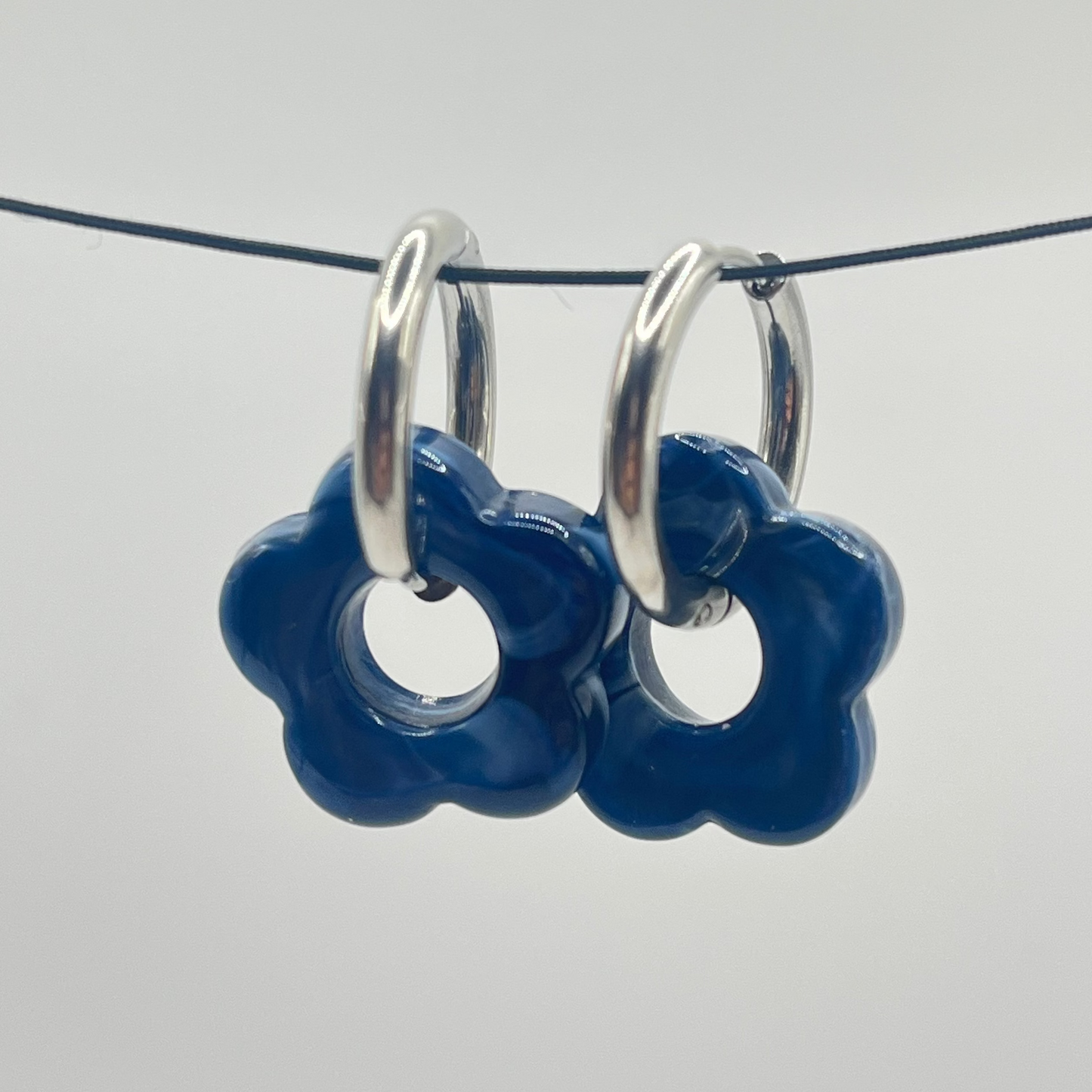 Pair of heavy blue flower-shaped earrings with silver loops on a white background
