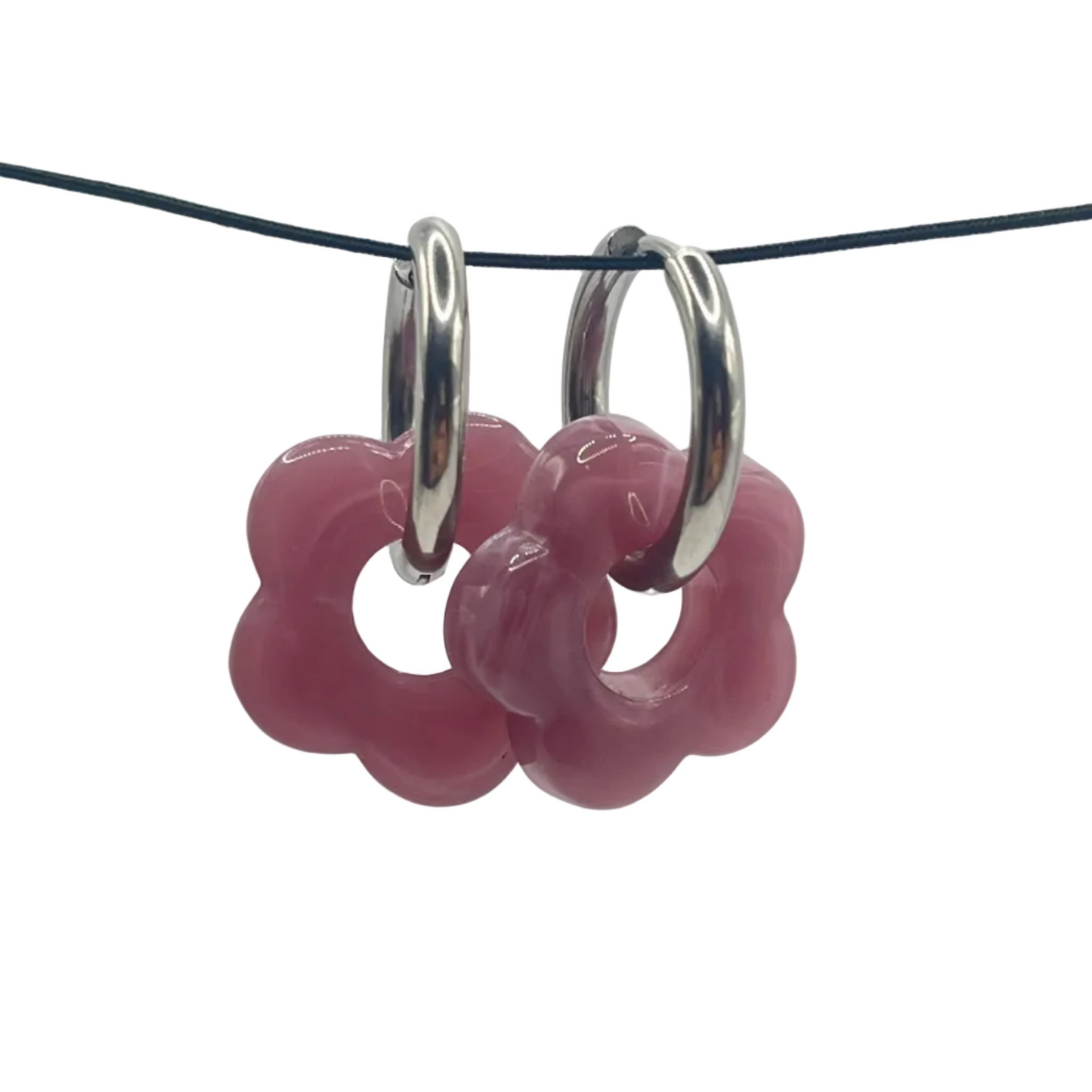 Pink flower-shaped earrings on a black wire against a light gray background