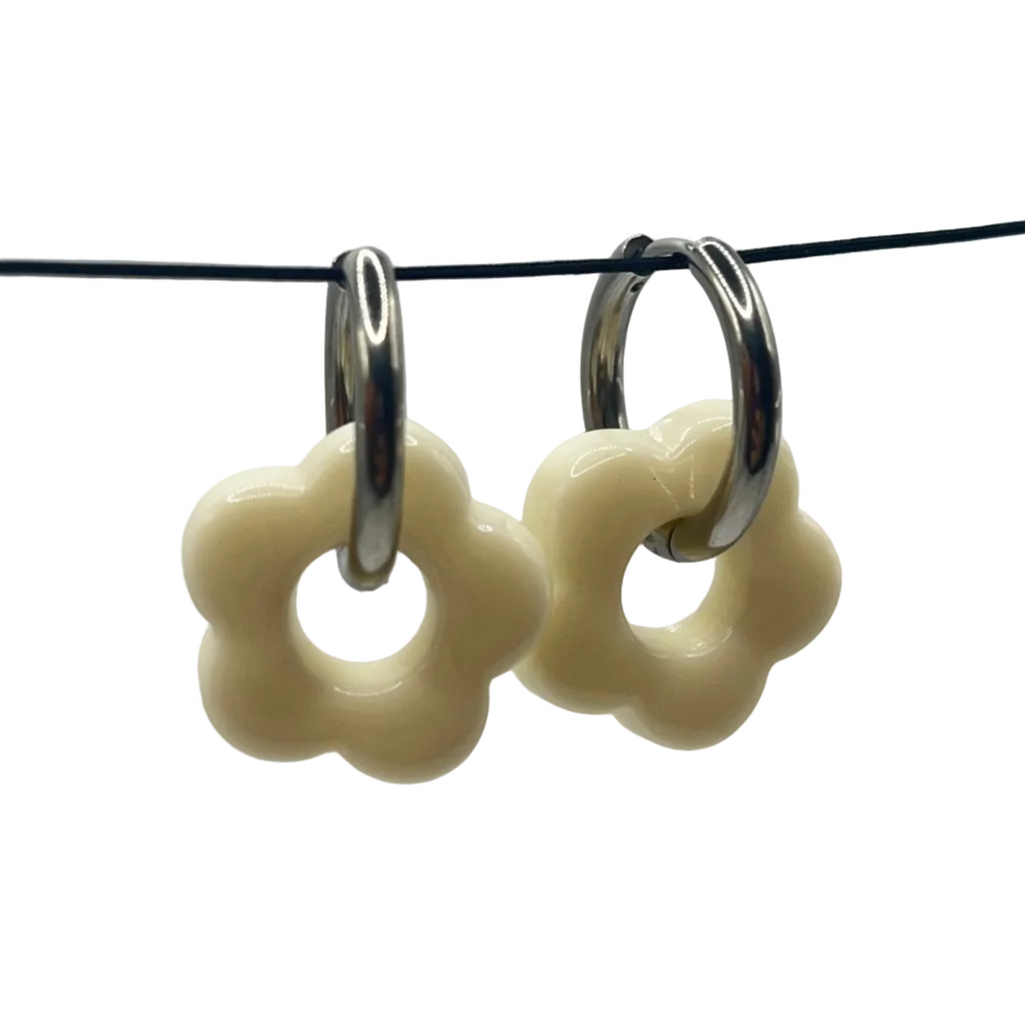 Flower-shaped earrings on a black cord against a light gray background