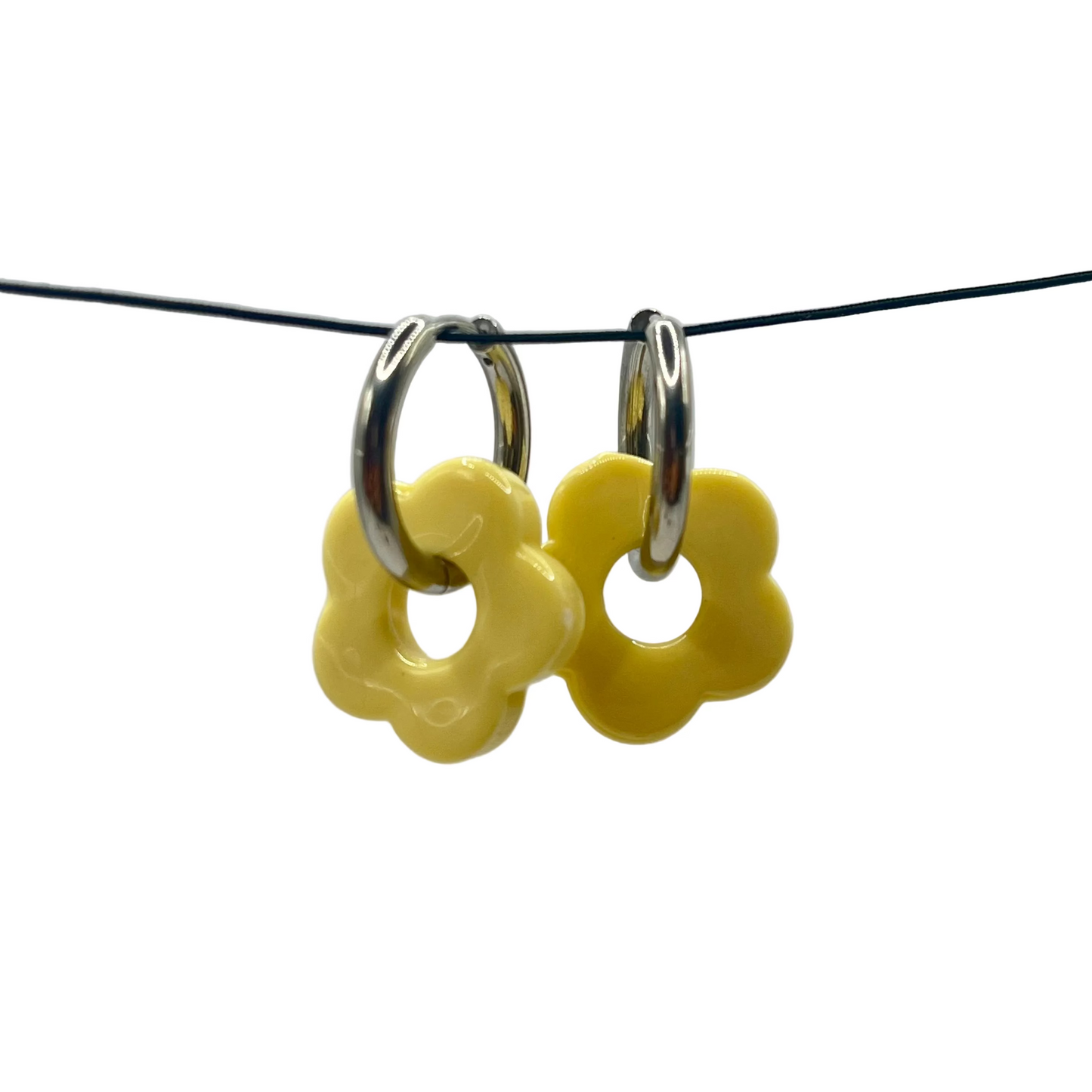 Yellow flower-shaped earrings on a black wire against a gray background