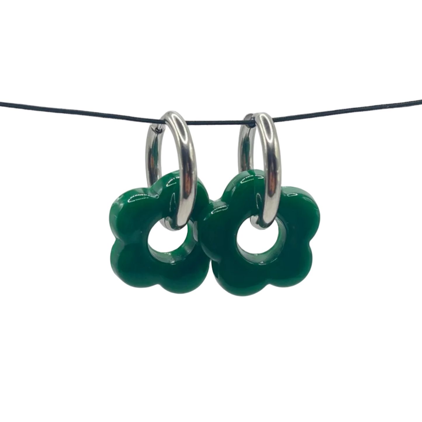 Green floral earrings on a black cord against a light gray background