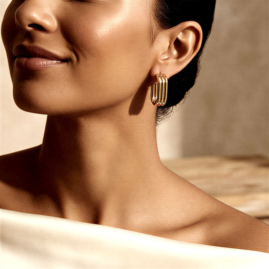 Close-up of a woman wearing gold hoop earrings with a neutral background