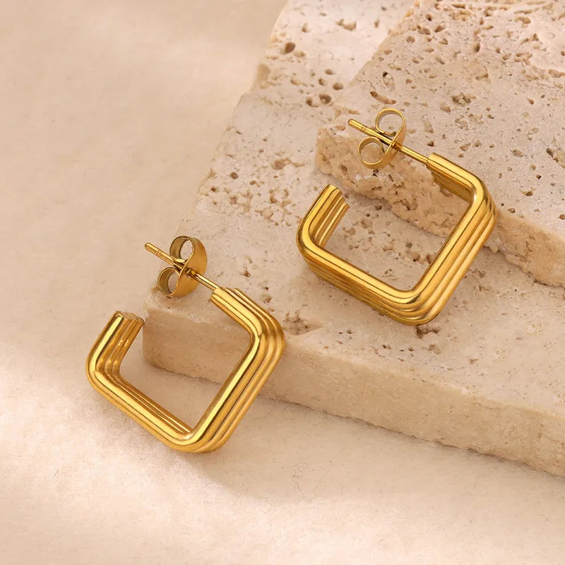 Gold hoop earrings on a textured beige surface