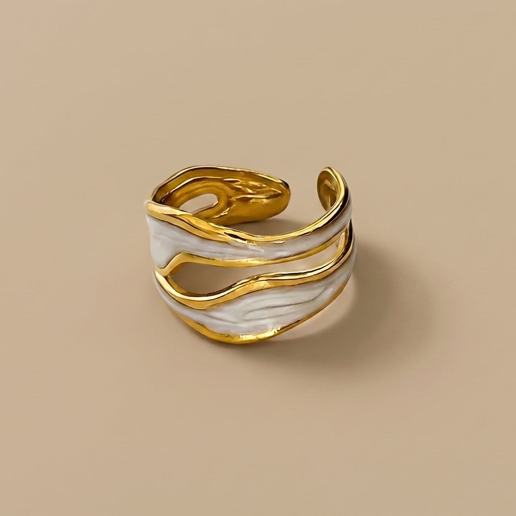 Gold and white marbled ring on a beige background with 'NORU' branding.