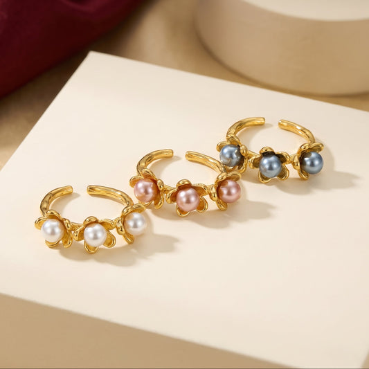 Gold hoop earrings with pearls on a beige surface, featuring the brand 'NORU'.