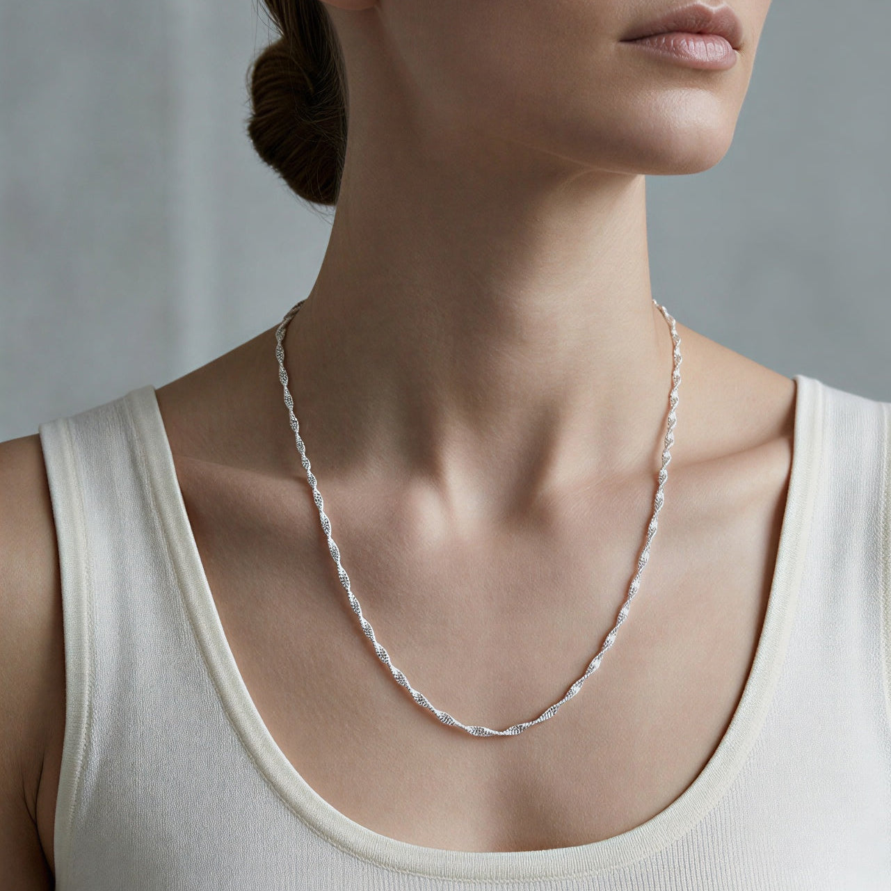 Necklace worn by a person in a white tank top against a neutral background