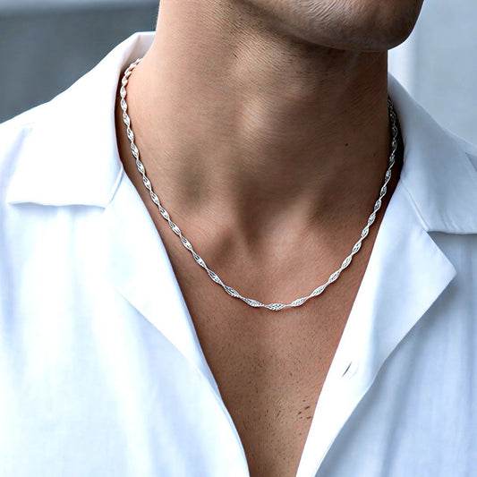Man wearing a white shirt and silver necklace with a blurred background