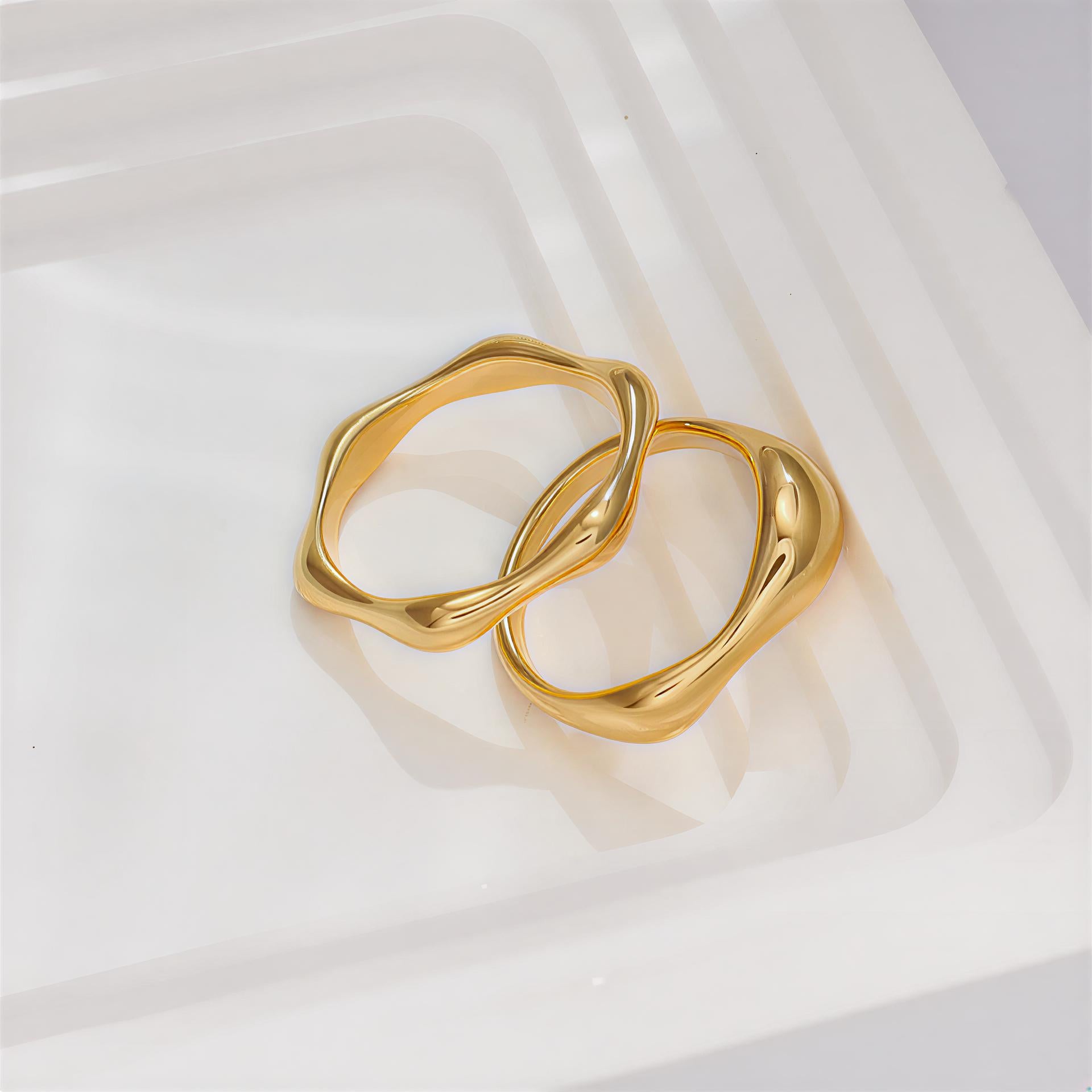 Two gold rings on a white fabric background