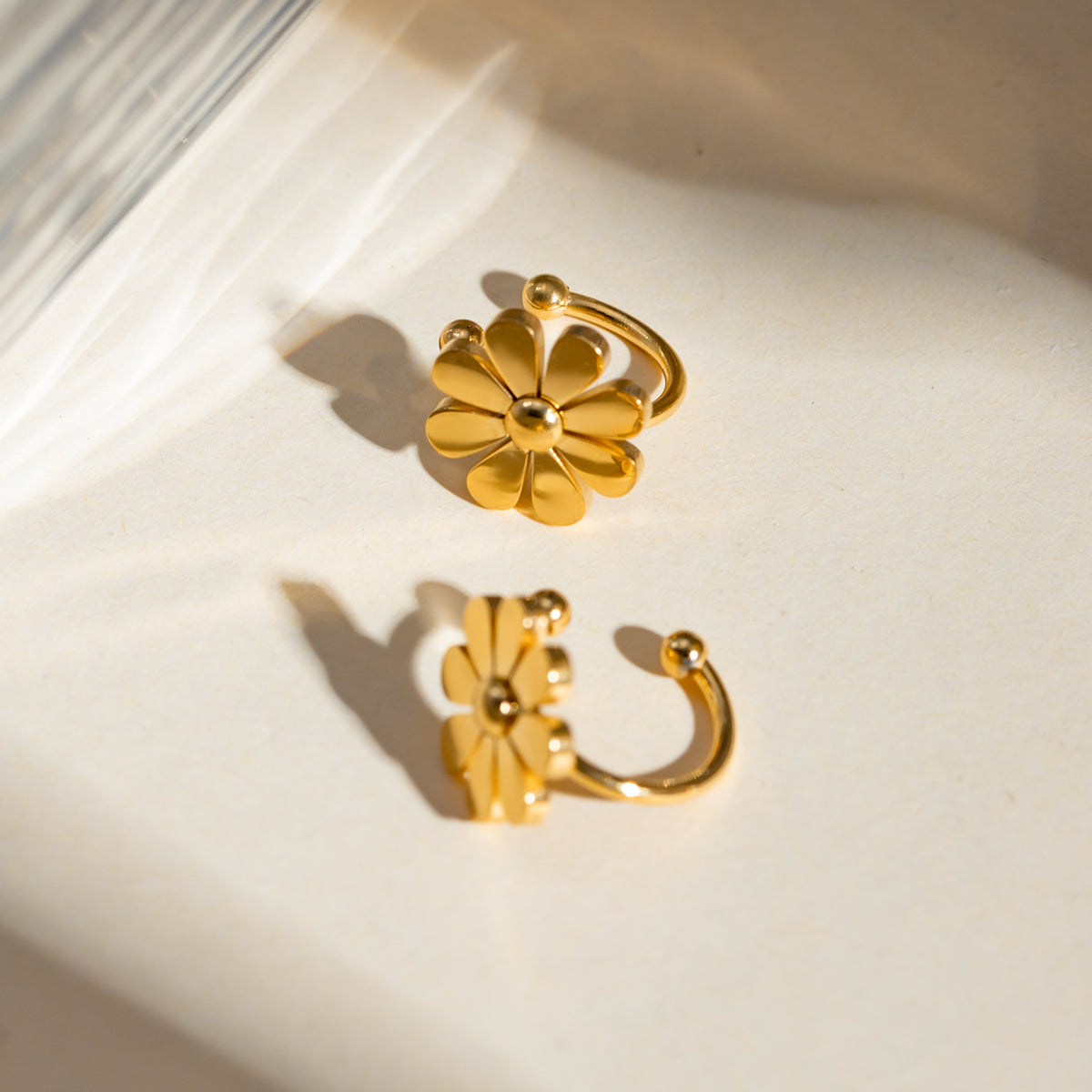 Gold flower-shaped earrings on a light background
